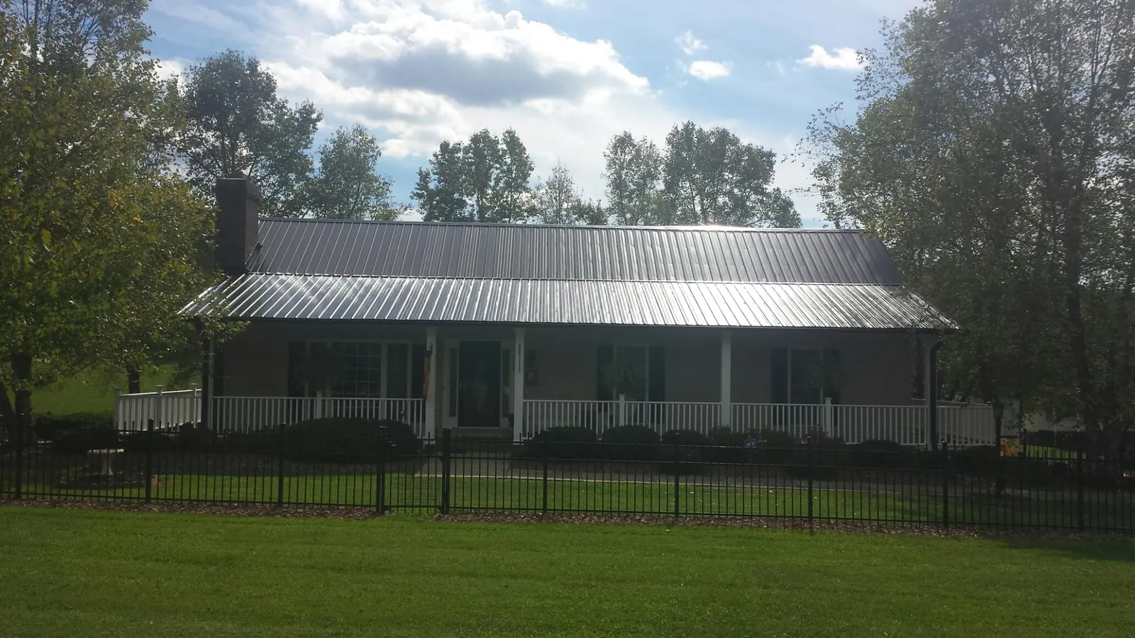 Gray metal roof on a brick ranch with a full width front porch — Gutter Guard Installation work by our crew in Ramey