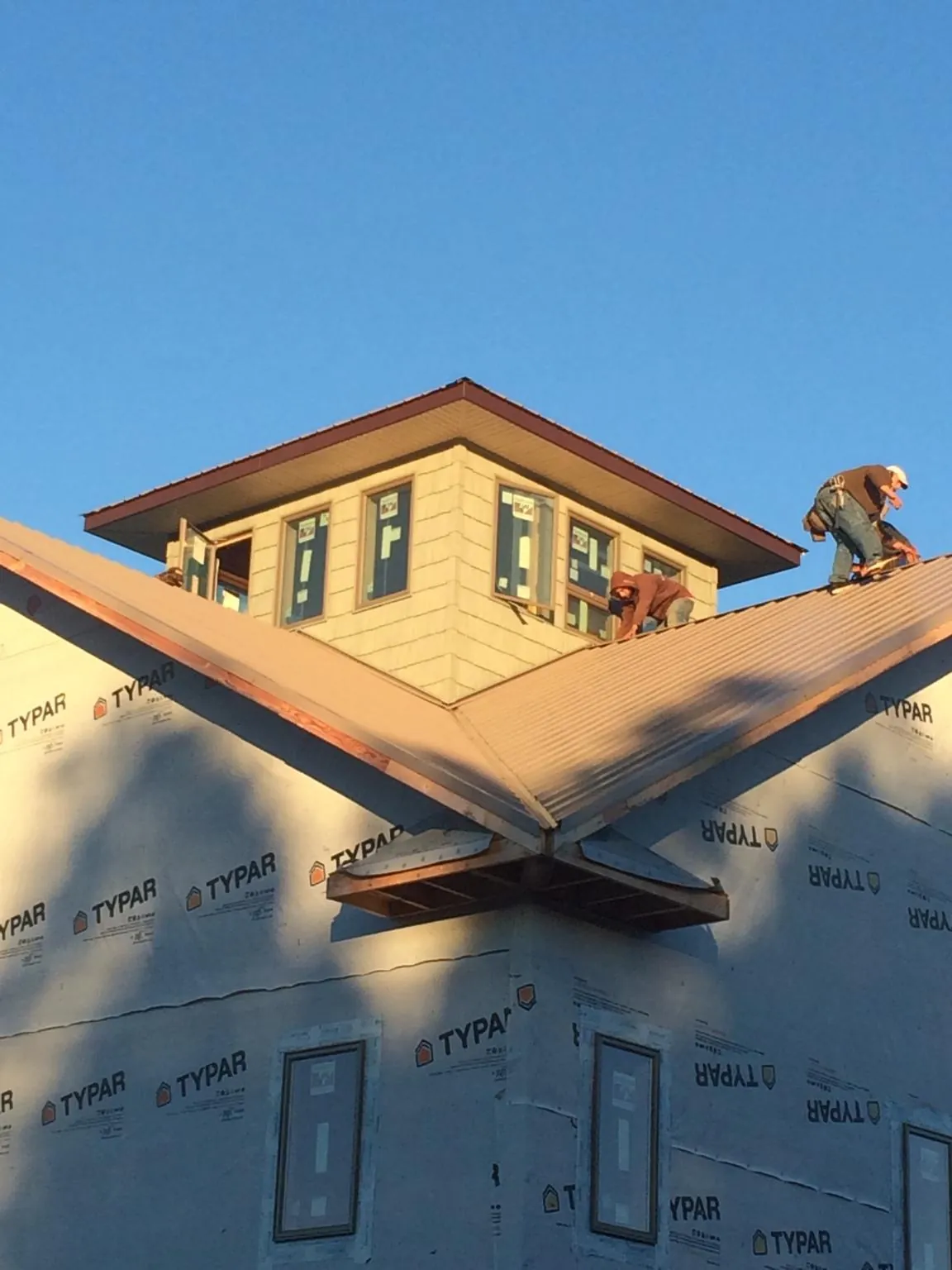 Roofers working around a rooftop cupola on a new metal roof at sunset — Roof Waterproofing in Ramey by Roofing Brothers